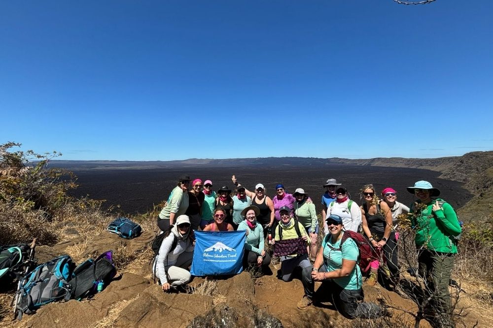 sierra negra volcano group of travelers hiking at sierra negra volcano, overlooking vast lava fields and volcanic landscapes on isabela island