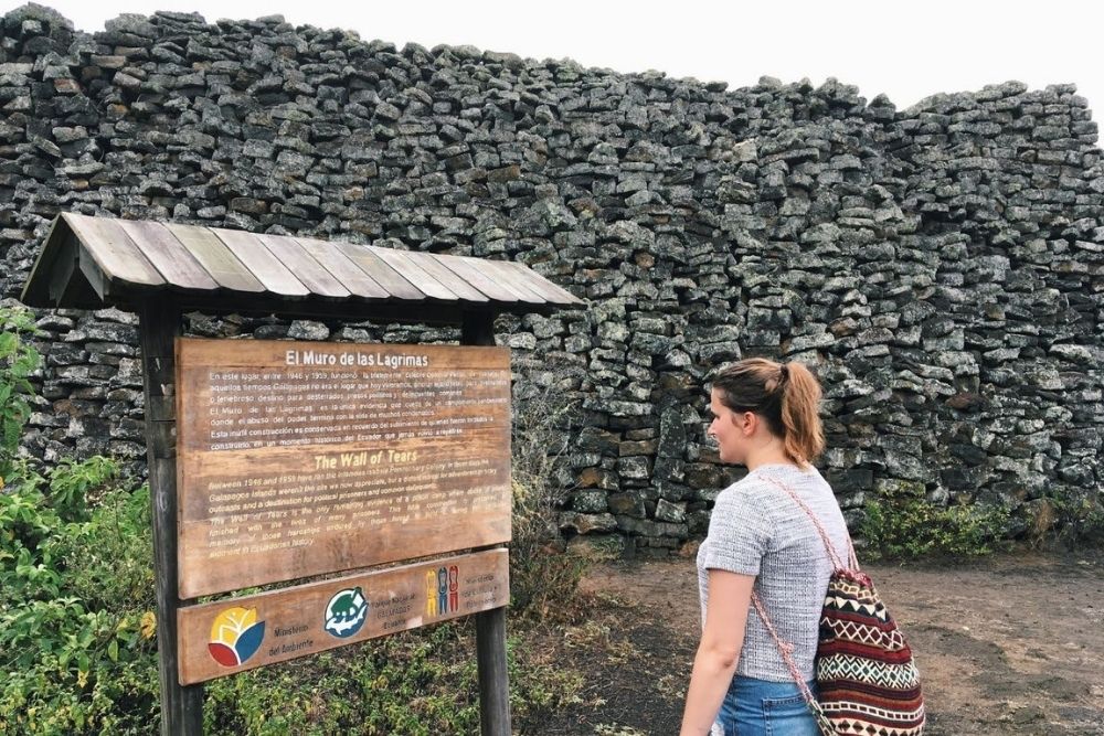 wall of tears at isabela island visitor reading the wall of tears monument on isabela island, a historic lava stone memorial from the galapagos past.